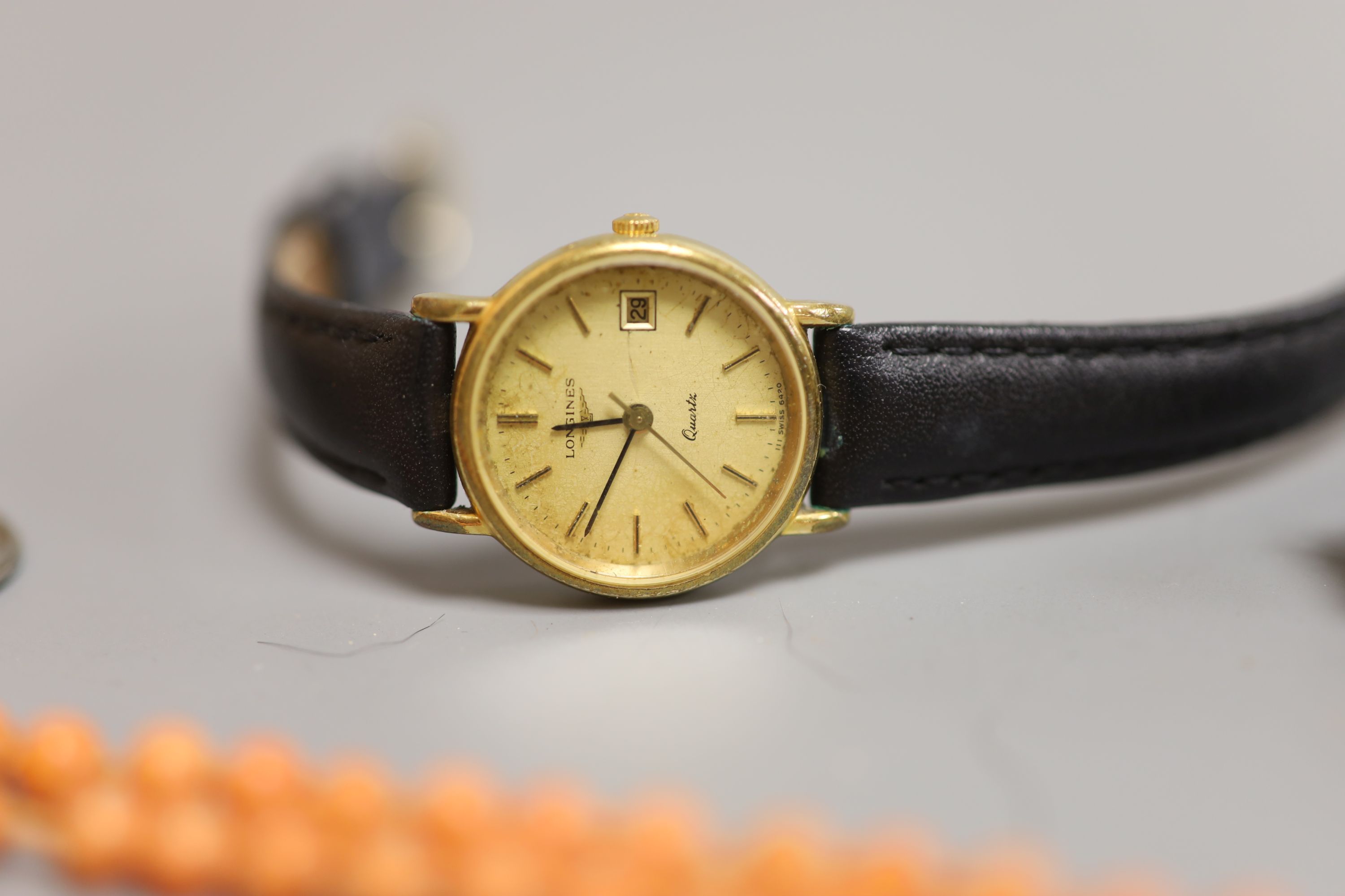 A lady's Longines gold plated and steel quartz wristwatch, one other watch, a coral bead necklace, badges etc.